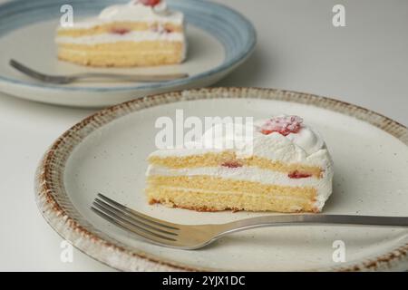 Shortcake e forchetta di fragole giapponesi su ogni piatto grande e piccolo su un tavolo bianco. Foto Stock