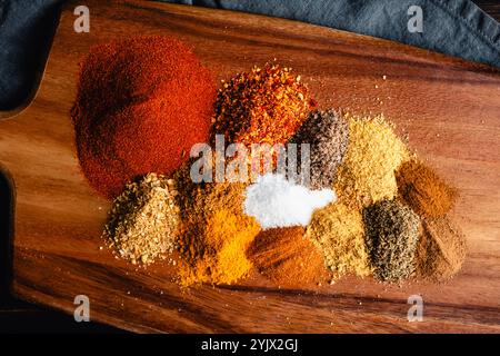 Ingredienti per la miscela di spezie Berbere sul tagliere primo piano: Erbe e spezie macinate per la miscela di spezie di Berbere etiope su un tagliere di legno Foto Stock