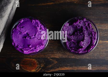 Purè di patate dolci viola in piccole ciotole di vetro: Confronto dei colori tra la purea fatta con patate dolci viola bollite (a sinistra) e tostate (a destra) Foto Stock