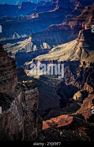 Le cascate di luce dorata del tramonto sul Grand Canyon rivelano i contorni intricati e le profonde formazioni rocciose stratificate all'interno del suo vasto canyon interno. Foto Stock