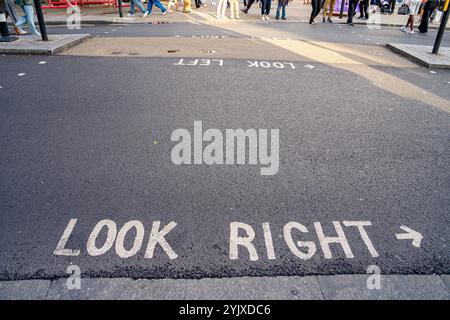 Strada asfaltata con informazioni scritte sul terreno: Guarda a destra, Londra. Foto Stock