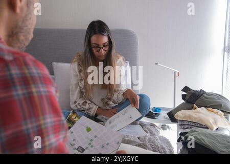 Un uomo e una donna sono seduti su un letto con un mucchio di vestiti davanti a loro. Nuovo concetto di casa. Foto Stock