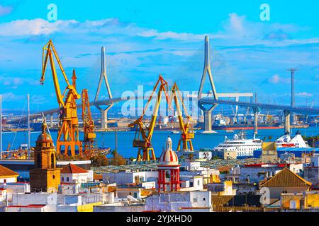 Cadice Spagna presenta una vivace città portuale con gru gialle, un ponte sospeso e un mix di edifici storici e moderni. La scena è vivace Foto Stock