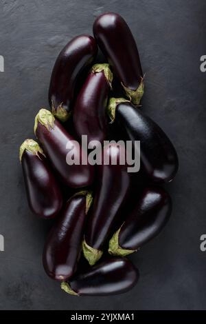 Mucchio di melanzane fresche mature su sfondo scuro, cibo biologico ecologico degli agricoltori locali, vista dall'alto Foto Stock
