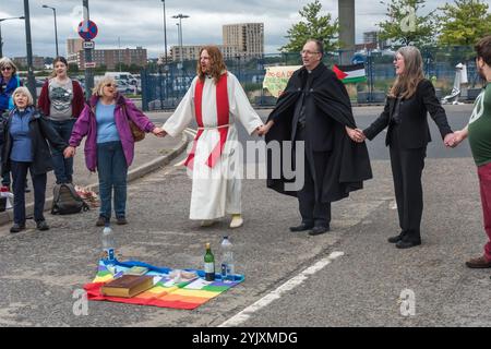 London, UK. 5th September 2017. People hold hands at the end of a mass on the road leading into the world's largest arms fair held in London's docklands. The series of events on the 'No Faith in War' day of the protests was organised by various faith groups. Before I arrived there had been a lock-in on the approach road stopping deliveries coming to set up the fair through the East gate. This was followed by a Quaker meeting at the side of the road during which a number of people stood or sat to block the road and several who refused to move were arrested. Then four protesters descended on rop Stock Photo