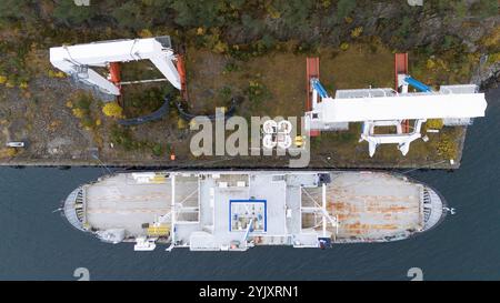 Vista aerea di una nave ancorata in un porto abbandonato con due grandi gru su entrambi i lati. La nave è posizionata parallelamente al litorale, circondata da b Foto Stock