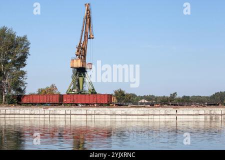 La gru a portale e le carrozze ferroviarie merci si trovano sulla costa nel porto di Ruse, Bulgaria Foto Stock