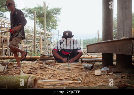 Un uomo si sta concentrando sulla legatura di pezzi di bambù tagliati nella zona di Tana Toraja, 3 ottobre 2024, Sulawesi meridionale, Indonesia Foto Stock