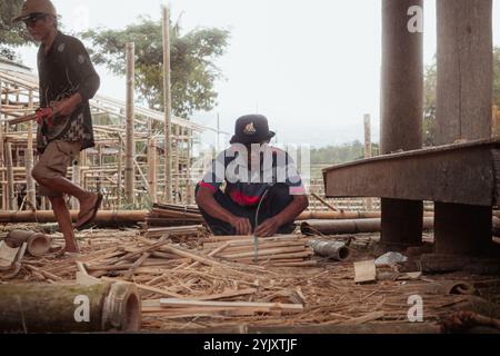 Un uomo si sta concentrando sulla legatura di pezzi di bambù tagliati nella zona di Tana Toraja, 3 ottobre 2024, Sulawesi meridionale, Indonesia Foto Stock