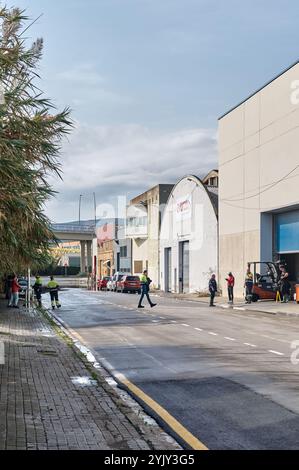 Viladecans. Spagna - 16 novembre 2024: Gruppo di lavoratori industriali che entrano ed escono da un magazzino a Viladecans, con un carrello elevatore posizionato in Foto Stock