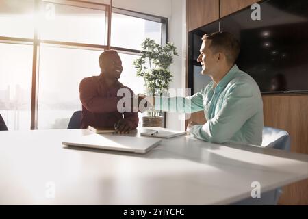 Giovani uomini d'affari afroamericani e caucasici felici che si accordano Foto Stock