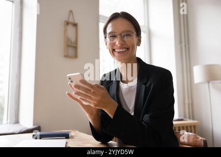 Ritratto di una donna d'affari felice, dipendente dell'ufficio che utilizza lo smartphone sul posto di lavoro Foto Stock