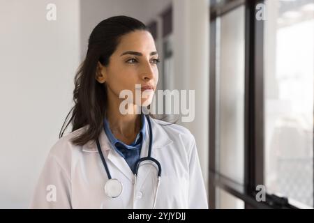 Una donna brasiliana premurosa che guarda fuori dalla finestra Foto Stock