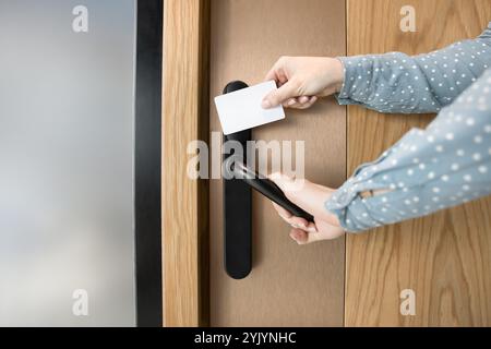 Colpo ritagliato di mani femminili che aprono la porta con la chiave a scheda Foto Stock