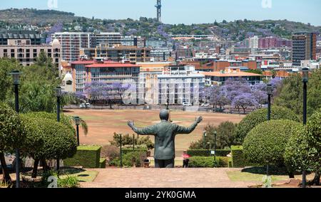 Vista posteriore della statua di Nelson Mandela e del giardino degli Union Buildings, Pretoria, Sudafrica. Alberi di jacaranda in fiore sullo sfondo Foto Stock