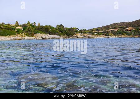 Spiaggia Cala Caterina presenta una pittoresca scena sarda: Acque cristalline e calme della baia si incontrano con sabbia soffice e formazioni rocciose, creando un ambiente sereno e invit Foto Stock