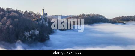 Sole sulle montagne, nebbia nella valle di Echaz. Castello di Lichtenstein nell'alb. Svevo. Il castello fiabesco di Wuerttemberg è un cas del XIX secolo Foto Stock