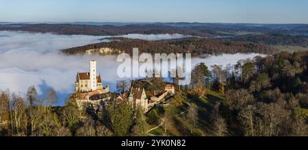 Sole sulle montagne, nebbia nella valle di Echaz. Castello di Lichtenstein nell'alb. Svevo. Il castello fiabesco di Wuerttemberg è un cas del XIX secolo Foto Stock