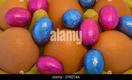 uova di cioccolato in folio tra uova crude. Informazioni generali sul concetto di Pasqua Foto Stock