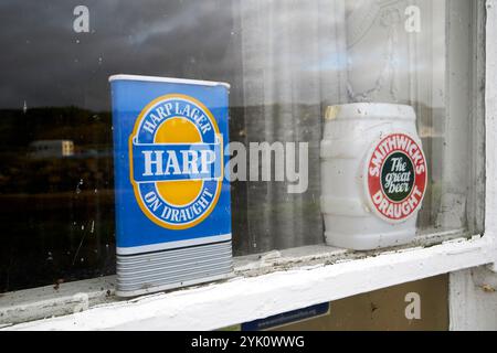 la vecchia lager dell'arpa e i cartelli della birra alla spina si trovano alla finestra del vecchio hotel cushendun, nella contea di antrim, nell'irlanda del nord Foto Stock