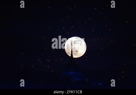 La luna piena sorge dietro l'impronta del Buddha di Yonok City, accompagnata da lanterne galleggianti in stile Lanna nel giorno del Loy Krathong al Wat Phra That Doi Saket. Foto Stock