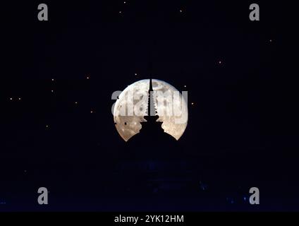 Chiang mai, Thailandia. 16 novembre 2024. La luna piena sorge dietro l'impronta del Buddha di Yonok City, accompagnata da lanterne galleggianti in stile Lanna nel giorno del Loy Krathong al Wat Phra That Doi Saket. (Foto di Pongmanat Tasiri/SOPA Images/Sipa USA) credito: SIPA USA/Alamy Live News Foto Stock