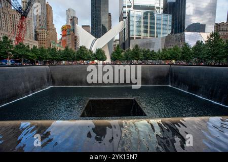 Questa immagine raffigura il 911 Memorial a New York City, con la fontana illuminata a cascata circondata da moderni grattacieli, Manhattan, New Yo Foto Stock