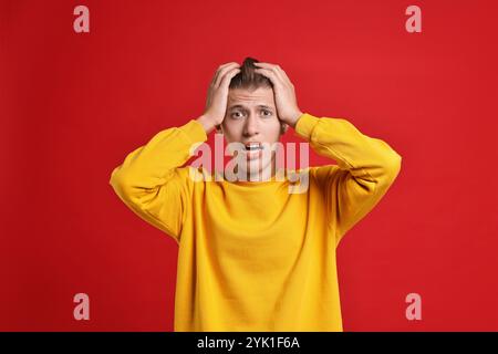 Studente emotivo che ha stress prima dell'esame su sfondo rosso Foto Stock