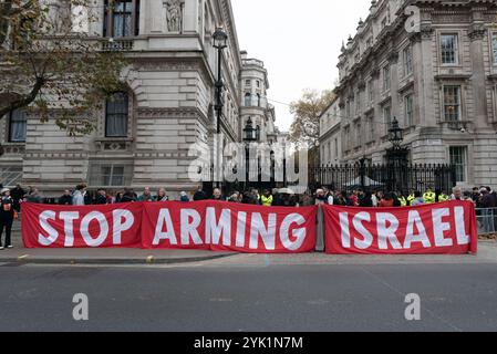 Londra, Regno Unito. 16 novembre 2024. Uno striscione esposto fuori Downing Street chiede al Regno Unito di smettere di armare Israele dopo una marcia da parte di una coalizione di oltre sessanta gruppi per la campagna sul clima e di molti sostenitori palestinesi che invitano il governo a intraprendere maggiori azioni per combattere il cambiamento climatico mentre si unisce ai colloqui sul clima COP 29 in Azerbaigian. La marcia è iniziata al British Museum, che riceve la sponsorizzazione dalla compagnia petrolifera BP e gestisce i campi petroliferi in Azerbaigian, da dove si stima che il 30% del petrolio di Israele sia fornito da gasdotti attraverso la Turchia. Crediti: Ron Fassbender/Alamy Live News Foto Stock