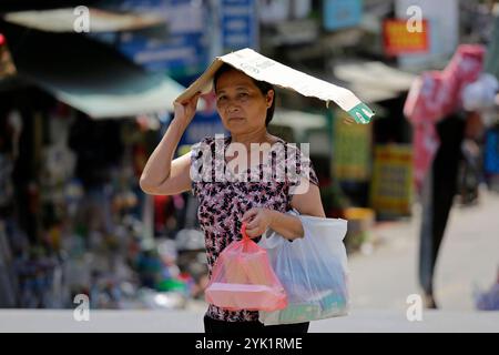 Hanoi, Vietnam - 2 luglio 2023: Donna si protegge dal sole estremo caldo mentre cammina per una strada durante una forte ondata di caldo. Foto Stock