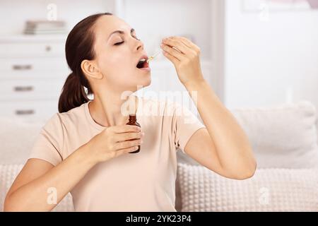 Giovane donna che prende tintura CBD all'interno. Estratto di erbe Foto Stock