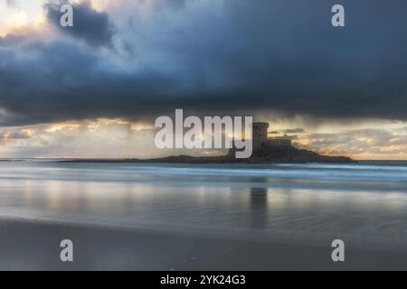 La Torre la Rocco sorge sulla spiaggia sabbiosa al tramonto. Il cielo si riflette nell'acqua. Foto Stock