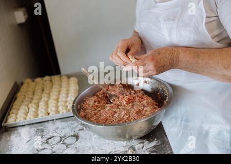Preparazione manuale di gnocchi tradizionali con ripieno di carne fresca in un ambiente domestico da cucina Foto Stock