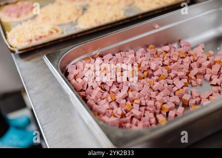 Pezzi di prosciutto a dadini preparati per preparare dolci salati in un ambiente professionale da cucina Foto Stock