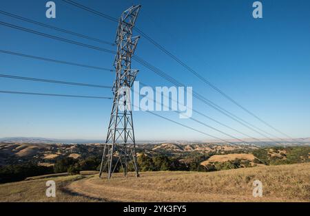 Linee elettriche ad alta tensione e torri si uniscono in molte parti del Briones Regional Park District (http://www.ebparks.org/parks/briones) di 6.255 acri dell'East Bay Regional Park District nella contea di Contra Costa, CA, venerdì 24 luglio 2015. Operando completamente "fuori dalla rete" il rancher Ned Woods del Dipartimento dell'Agricoltura degli Stati Uniti ha installato pannelli solari per utilizzare l'energia solare per alimentare una pompa elettrica di pozzi che aspira acqua da centinaia di metri sotto la superficie e spinge l'acqua lungo chilometri di tubo fino a centinaia di canoni di elevazione fino a un sistema di irrigazione remota automatizzata Foto Stock