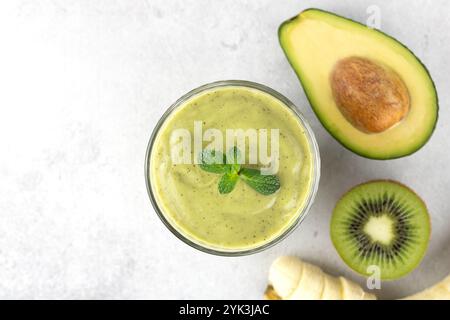 Frullato di avocado su sfondo grigio, vista dall'alto. Frullato verde con avocado, kiwi e banana, spazio copia. Foto Stock