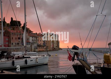 Rovigno, Istria, Croazia;16 ottobre 2024: Il fascino del mare di Rovigno, Istria, mentre il sole tramonta, dipingendo il cielo di un rosso vibrante. In primo piano, Foto Stock