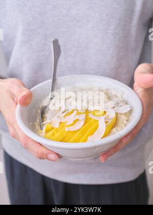 Avena notturna con mango e fiocchi di cocco appena tagliati Foto Stock