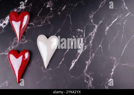 Romantici cuori di porcellana rossa e bianca, adagiati su marmo nero, che enfatizzano l'amore e l'eleganza per una celebrazione di San Valentino Foto Stock