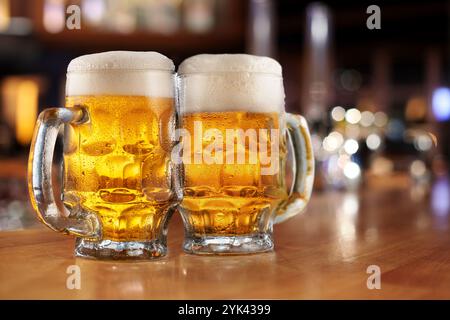 Due bicchieri di birra con schiuma di birra e gocce d'acqua sul bancone del bar del pub. Foto Stock