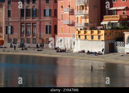 Sestri Levante, Italia - 14 novembre 2024. La gente prende il sole e nuota in autunno nella Baia del silenzio in mare. Turismo e svago. Ecologicamente pulito Foto Stock