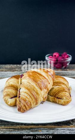 Due croissant, ripieni di una confettura di frutta, sono esposti su un piatto bianco. Foto Stock