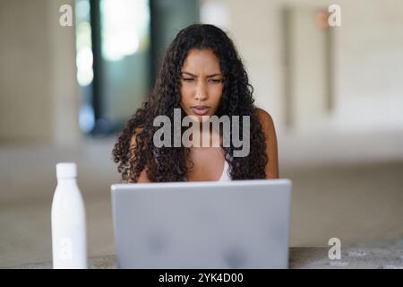 Una donna concentrata che lavora diligentemente sul proprio notebook in un ambiente di lavoro moderno ed elegante Foto Stock