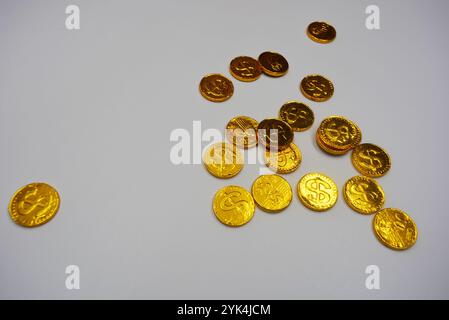 Belle, grandi monete d'oro, centesimi con il simbolo del dollaro si trovano su uno sfondo bianco di plastica. Caramelle dei soldi, una barretta di cioccolato in un metallo d'oro. Foto Stock