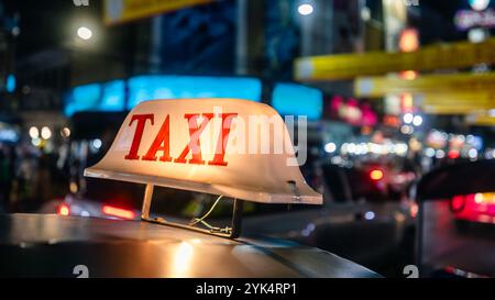 Cartello taxi illuminato sul tetto in tuk tuk di notte. Strada trafficata a Bangkok, Thailandia Foto Stock