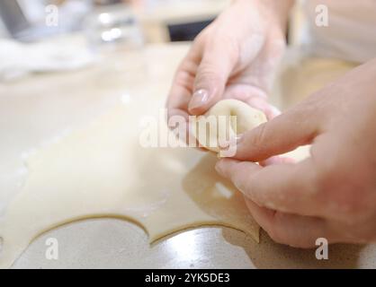 Una persona forma abilmente gnocchi a mano, mostrando l'intricato processo di preparazione di un piatto delizioso. Foto Stock