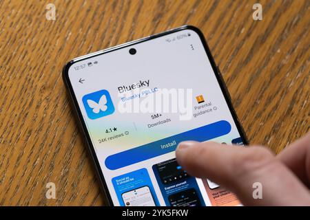 Persona che installa Bluesky su uno smartphone, Regno Unito. Un'app di social media che attrae follower da X. Un progetto finanziato da Twitter con maggiore moderazione Foto Stock