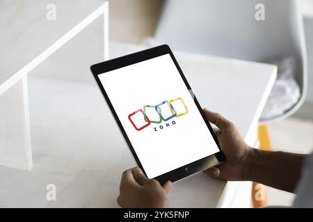 Persona che detiene un telefono cellulare con il logo della società tecnologica indiana Zoho Corporation sullo schermo del telefono Foto Stock