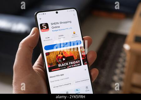 Tenere a mano la schermata di installazione Shein su uno smartphone con un annuncio Black Froday, Regno Unito. Shein è un rivenditore globale di moda e lifestyle online Foto Stock