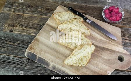 Quattro fette di croissant sono disposte su un tagliere di legno con coltello Foto Stock